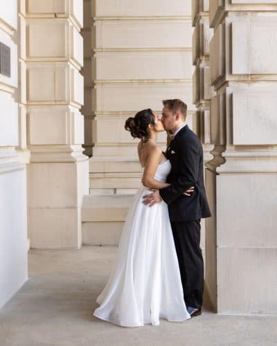 wedding couple poses in front of the courthouse arches on their wedding day